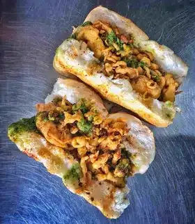 Vada Pav You’ll Regret Not Trying - Best Vada Pav in Mumbai 2 Tasty Vada Pavs set upside filled with golden brown petty covered in sauces o rather chutneys and chura.