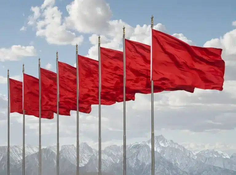 Snowy mountain landscape with prominent red flags against a backdrop of clear blue sky