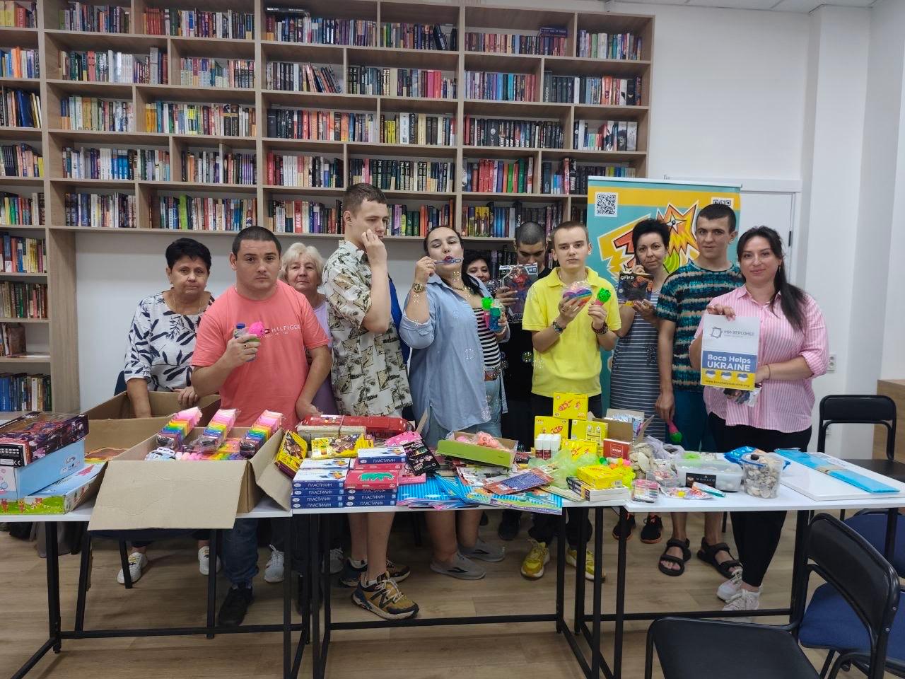 Children and adults behind a table of school supplies