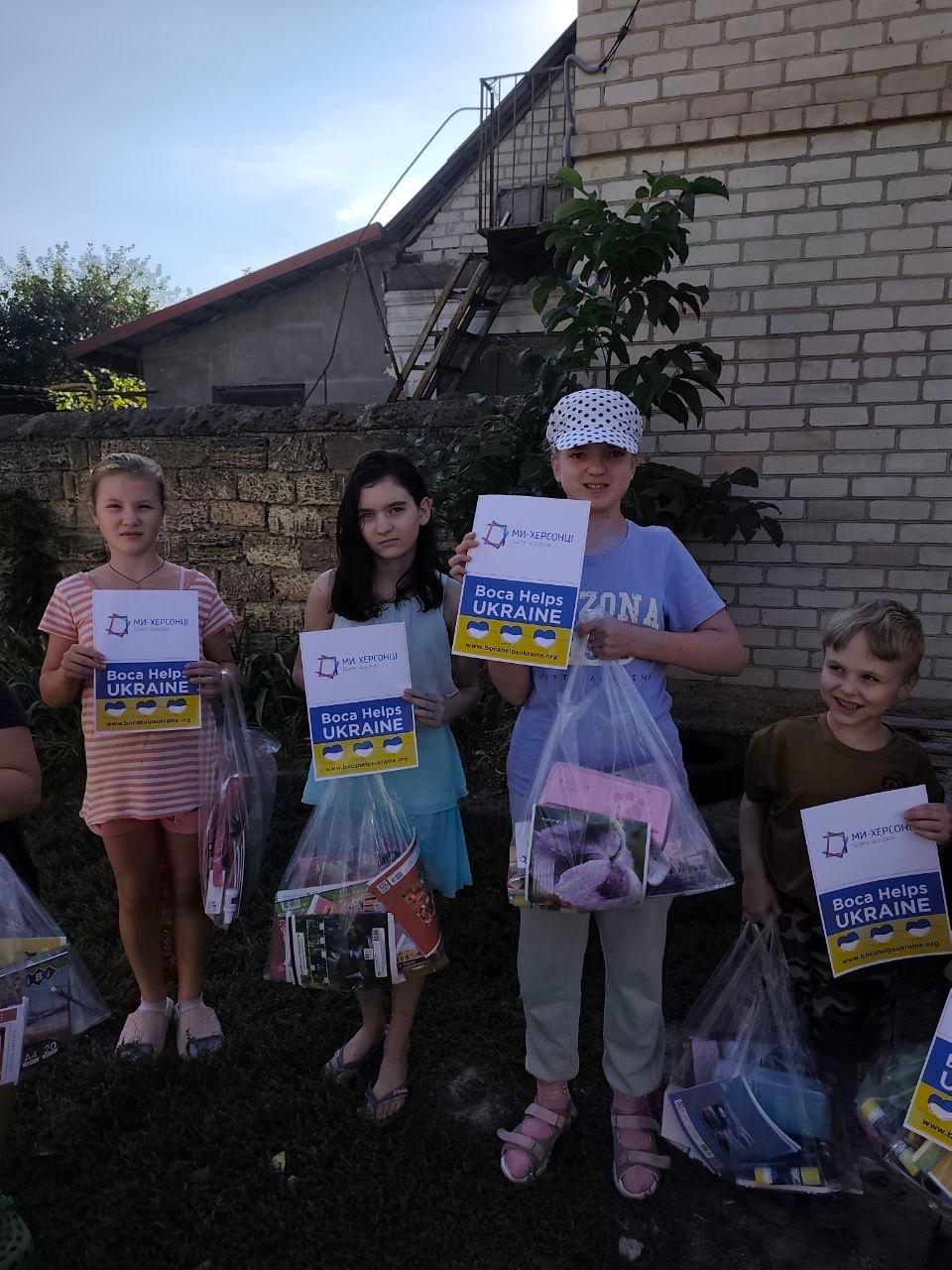 Children holding supplies and Boca Helps Ukraine signs outside