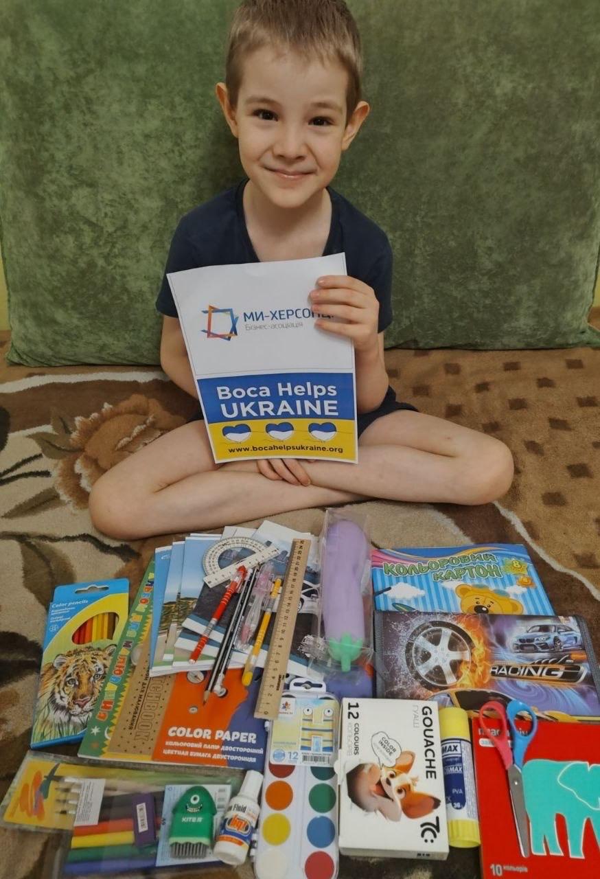 A child with school supplies arranged on a table
