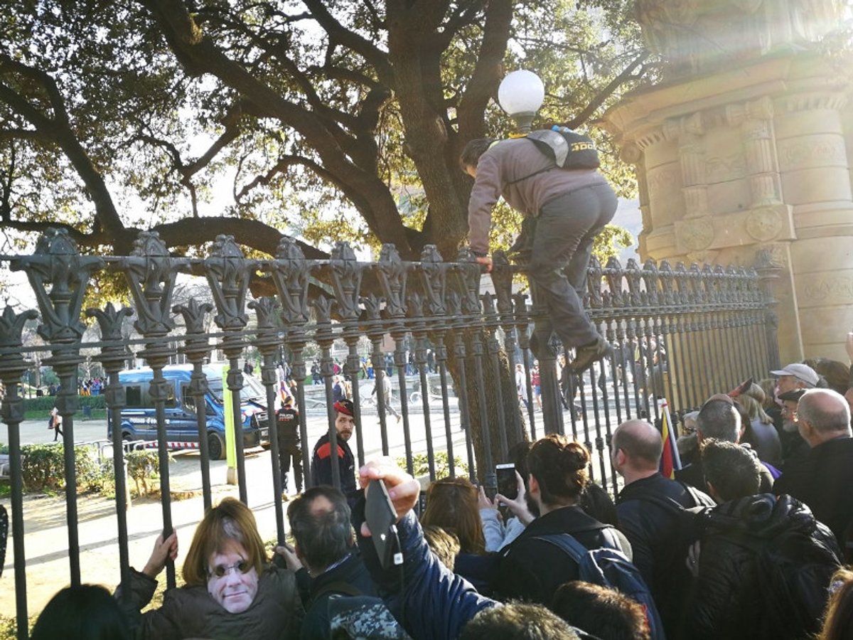 Un manifestant escala la tanca que separa els manifestants del Parlament