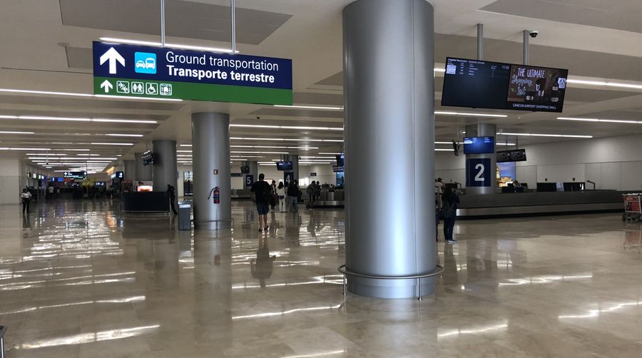 La señal de transporte terrestre en el Aeropuerto de Cancún. Los mostradores de taxi y ADO están del lado de llegadas.