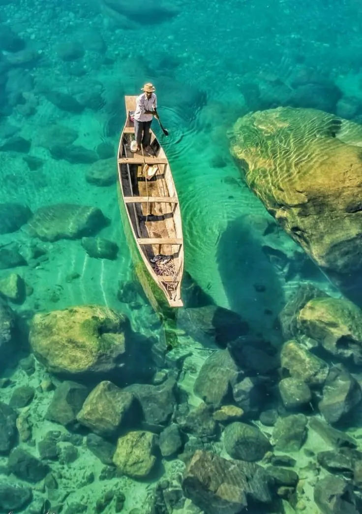 A boatman paddling a wooden canoe over the crystal-clear Umngot River in Dawki, Meghalaya