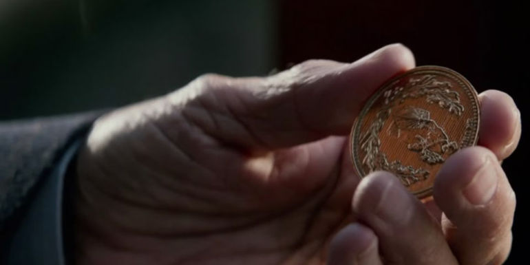 Someone holding a single gold coin in the John Wick movies