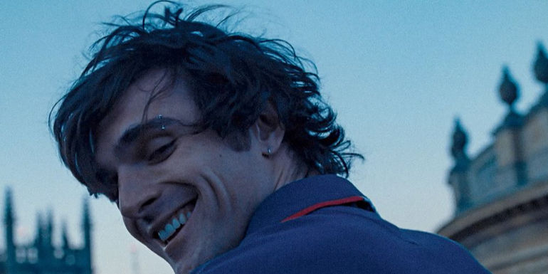 Felix looks backward and smiles in Saltburn.