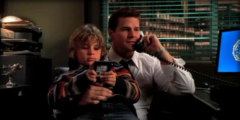 Seeley (David Boreanaz) talking on the phone with Parker (Ty Panitz) sitting on his lap in Bones.