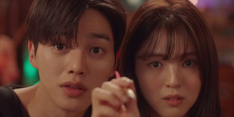 A closeup of a man and womans face while the woman holds a paintbrush in front of them in the K-drama Nevertheless