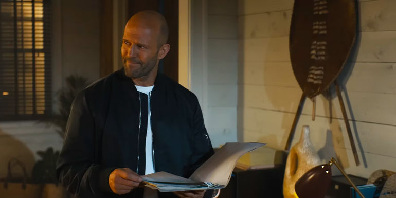 Jason Statham with a smirk holding some papers in Expendables 4