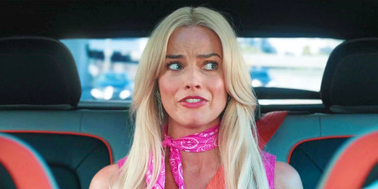 Margot Robbie Stereotypical Barbie biting her lip in the Barbie movie in the back of a car