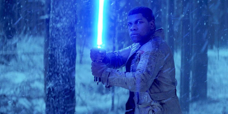 John Boyega as Finn wields a blue lightsaber in Star Wars: Episode VII - The Force Awakens.