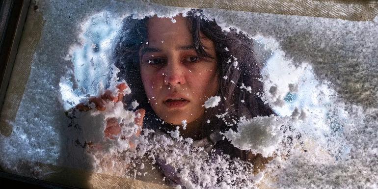 Teen Lottie cleaning snow off of the plane window in Yellowjackets