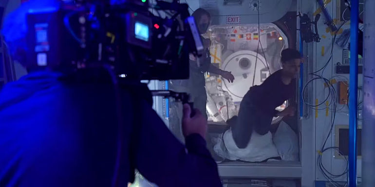 A still from the I.S.S. featurette shows a camera man filming Ariana DeBose hanging from a harness in I.S.S.