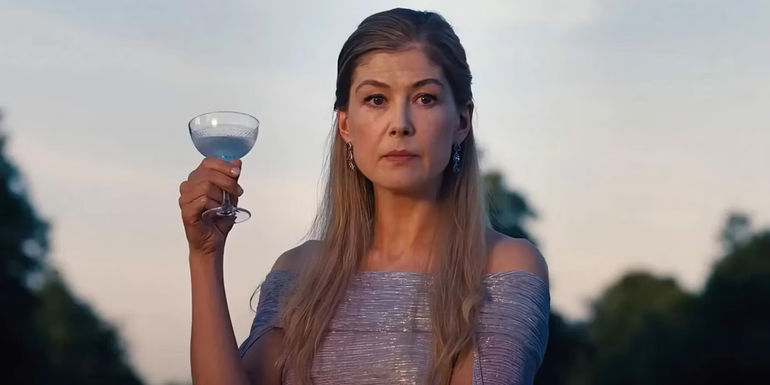 Rosamund Pike as Lady Elspeth Catton holds a cocktail and looks serious in Saltburn