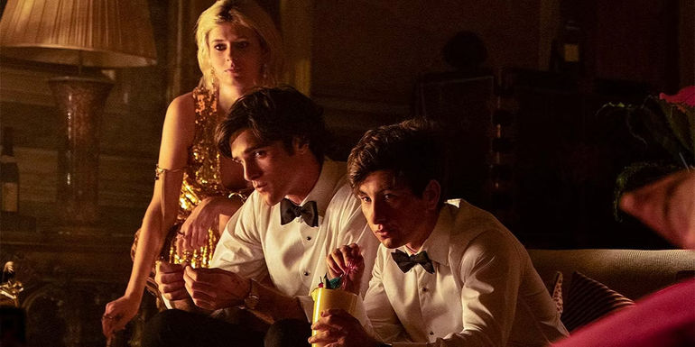 Venitia, Felix, and Oliver sitting together wearing party clothes in Saltburn