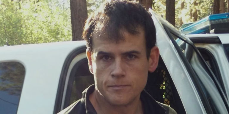 Matthew Muller standing outside police car