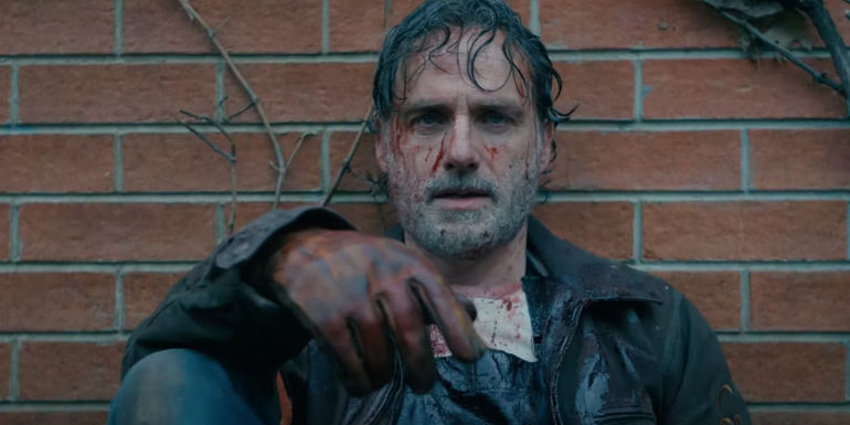A bloodied Rick Grimes (Andrew Lincoln) sitting against a brick wall in The Walking Dead: The Ones Who Live Trailer
