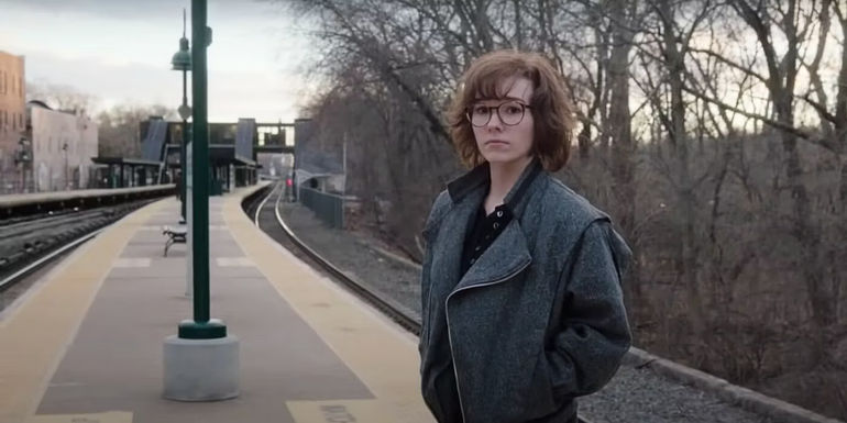 Holly Taylor as Paige Jennings standing on a train platform after leaving her parents in The Americans
