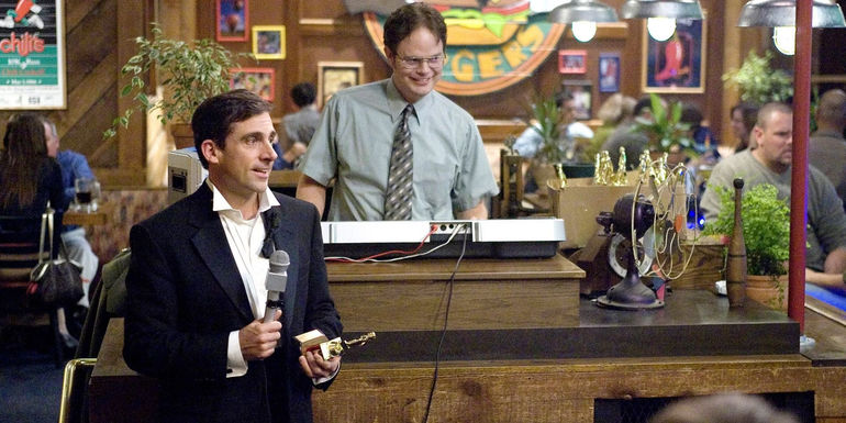 Michael holding a Dundie while Dwight MCs at the Dundies in The Office.