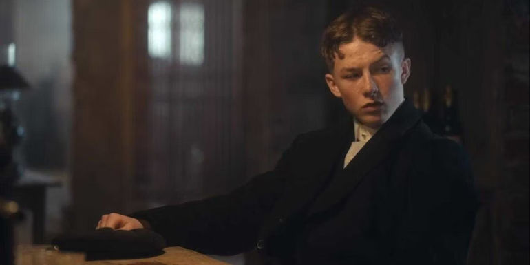 Finn Shelby sitting alone at the table at the Shelby business