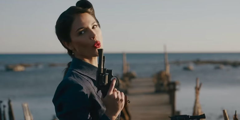 Eiza Gonzalez blowing smoke off the barrel of a gun in The Ministry of Ungentlemanly Warfare
