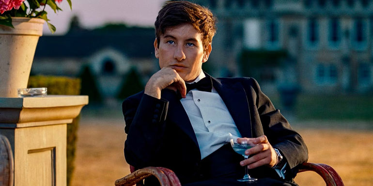 Oliver sitting outside with a drink in one hand in front of the Saltburn estate in Saltburn.