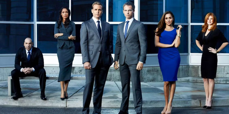 The cast of Suits is standing and posing for a picture.