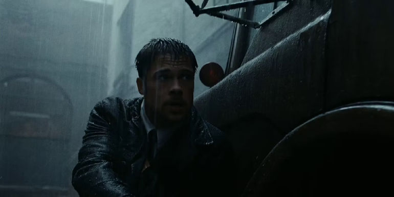 Brad Pitt as detective mills crouched behind a car in the rain in Seven (se7en)