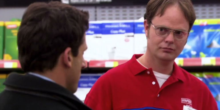 Rainn Wilson in a Staples uniform as Dwight Schrute talking to Steve Carell as Michael Scott in The Office