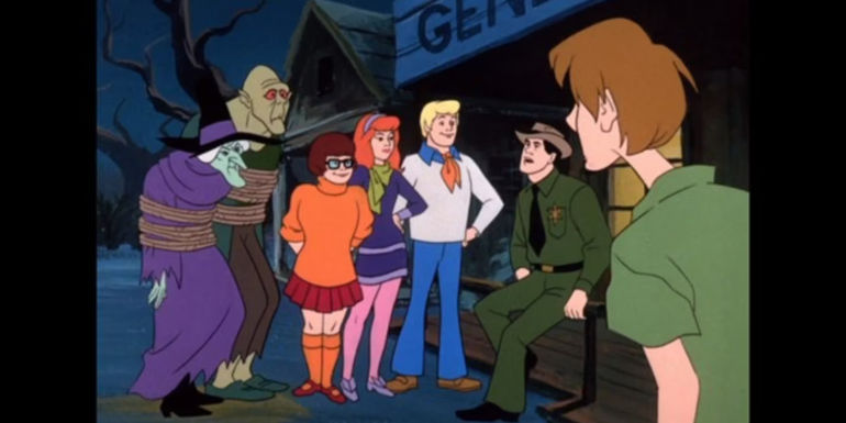 The gang and a sheriff with a tied up witch and zombie in Scooby-Doo