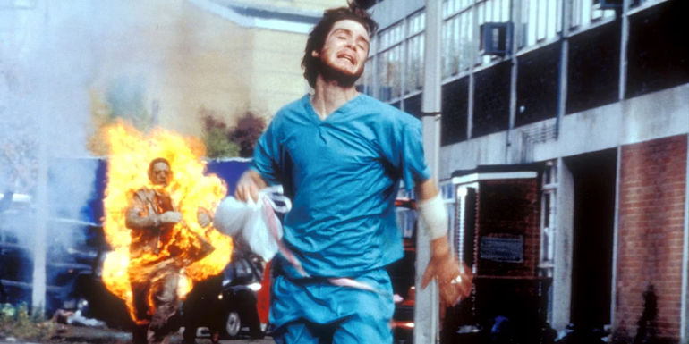 Cillian Murphy as Jim running away from a flaming zombie in 28 Days Later.