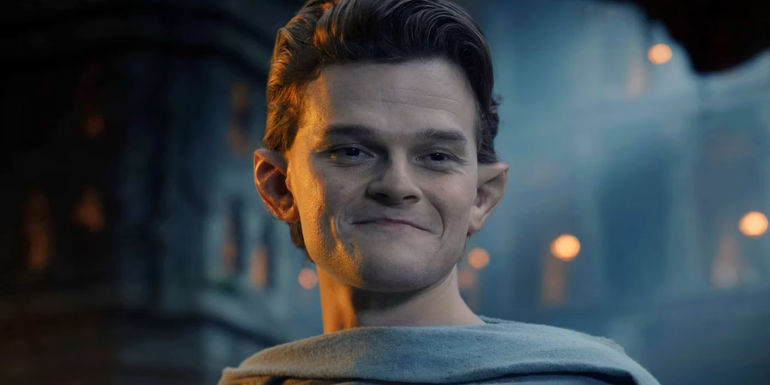 Robert Aramayo as Elrond looking down and smiling in The Rings of Power.