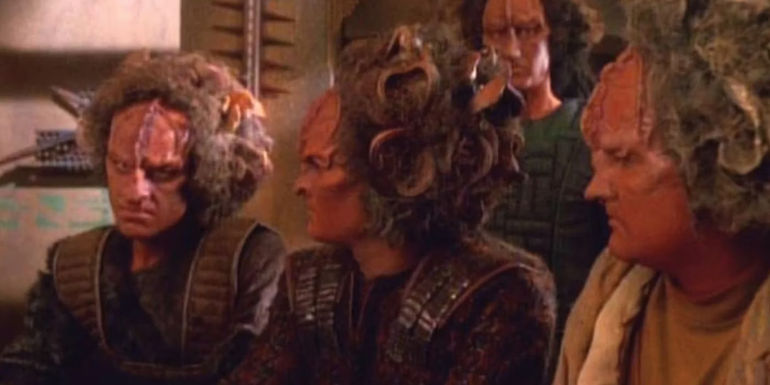 Several Kazon sit at a table speaking with each other in Star Trek: Voyager.