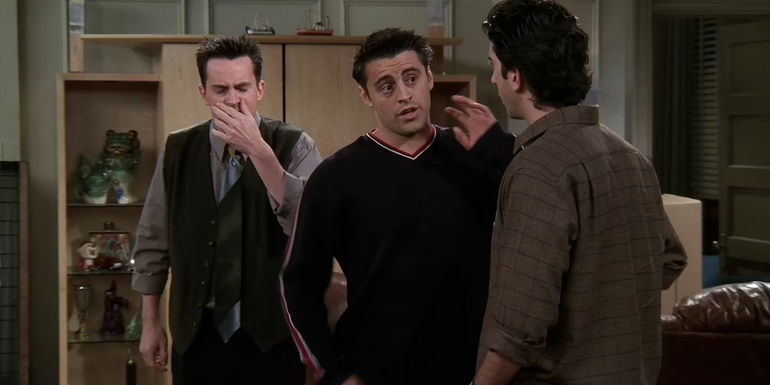 Joey talking to Ross in Friends while Chandler covers his mouth in the background