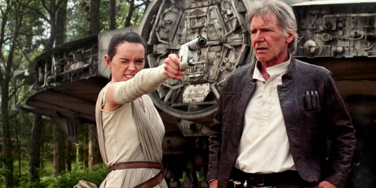 Rey (Daisy Ridley) points a gun while a stunned Han Solo (Harrison Ford) watches in Star Wars: Episode VII - The Force Awakens.
