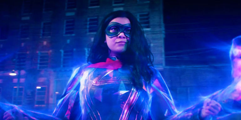 Kamala Khan (Ms. Marvel) stands in her superhero costume with her power all around her.
