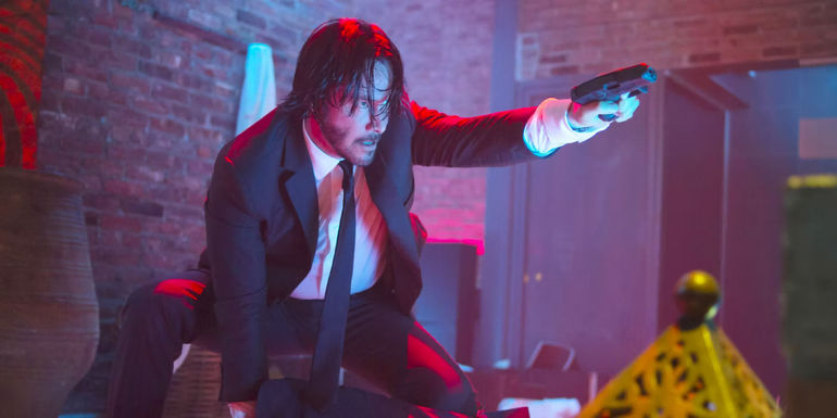 John Wick holding a gun in a club in John Wick