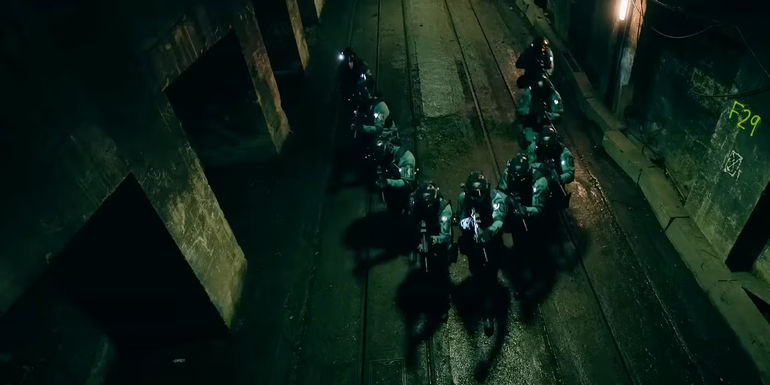 A tactical team with guns advances in a V formation in down a tunnel in Slow Horses season 3.