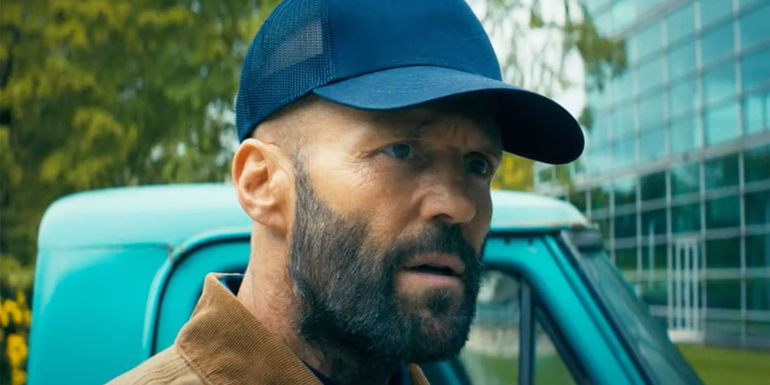 Clay from the Beekeeper standing in front of a truck parked outside of a large building