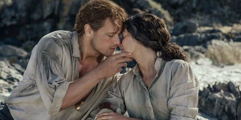 Jamie and Claire kiss while sitting on rocks in Outlander