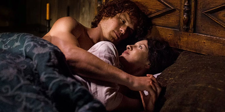 Jamie and Claire lay together looking at each other in bed in Outlander
