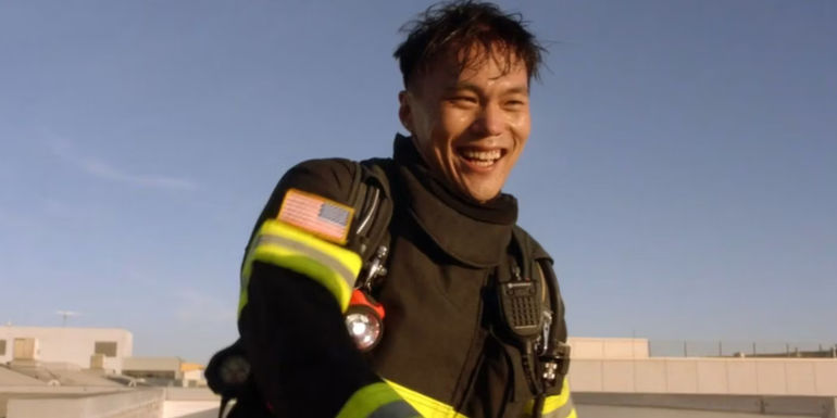 Albert Han (John Harlan Kim) wearing a fireman's uniform and smiling in 911.