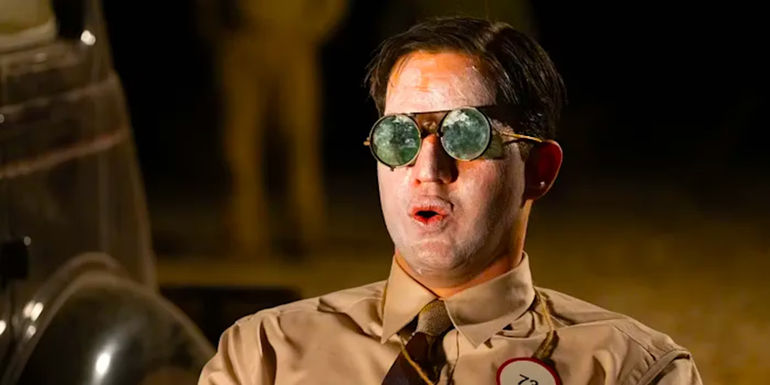 Benny Safdie wearing goggles, his face smeared in sunscreen, as he prepares for the Trinity test in Oppenheimer