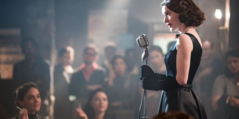 Midge stands on stage in black dress