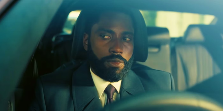 John David Washington as the Protagonist sits inside a car in Tenet.
