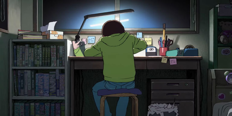 Look Back Anime Trailer featuring the main character in a green hoodie working at her desk.