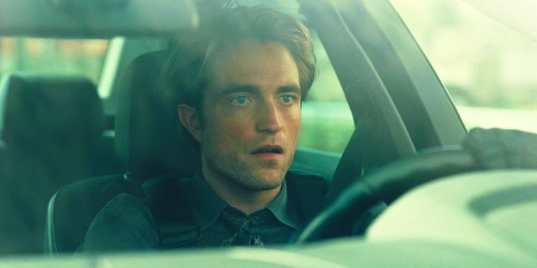 Robert Pattinson looking surprised behind the wheel of a car in Tenet.