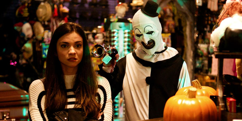 Art the Clown standing behind Sienna in a store in Terrifier 2