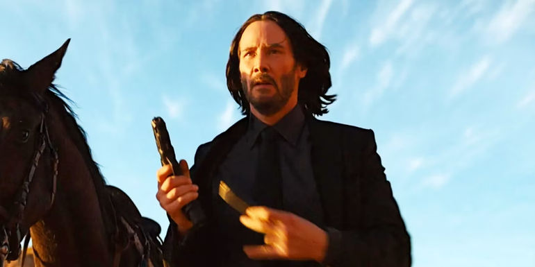 John Wick (Keanu Reeves) nạp súng bên cạnh một con ngựa trong John Wick: Chapter 4 - John Wick 5 Sẽ Ra Mắt Vào Khi Nào?