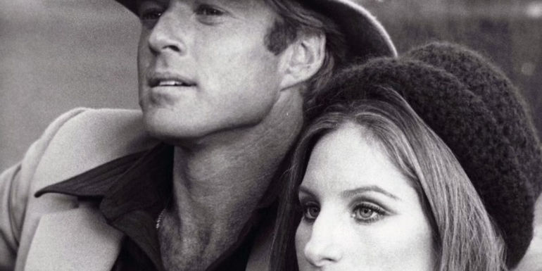 Robert Redford and Barbra Streisand looking off camera in The Way We Were